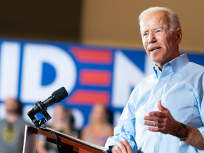 Close up of Joe at a podium giving a speech to a crowd. A Biden for President sign is visible in the background.